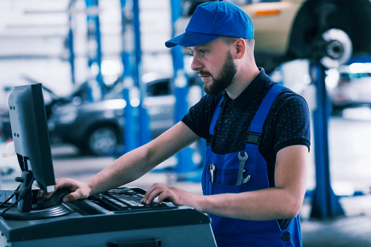 Mecânico usando o sistema para oficina mecânica da Wayssoft no computador da oficina